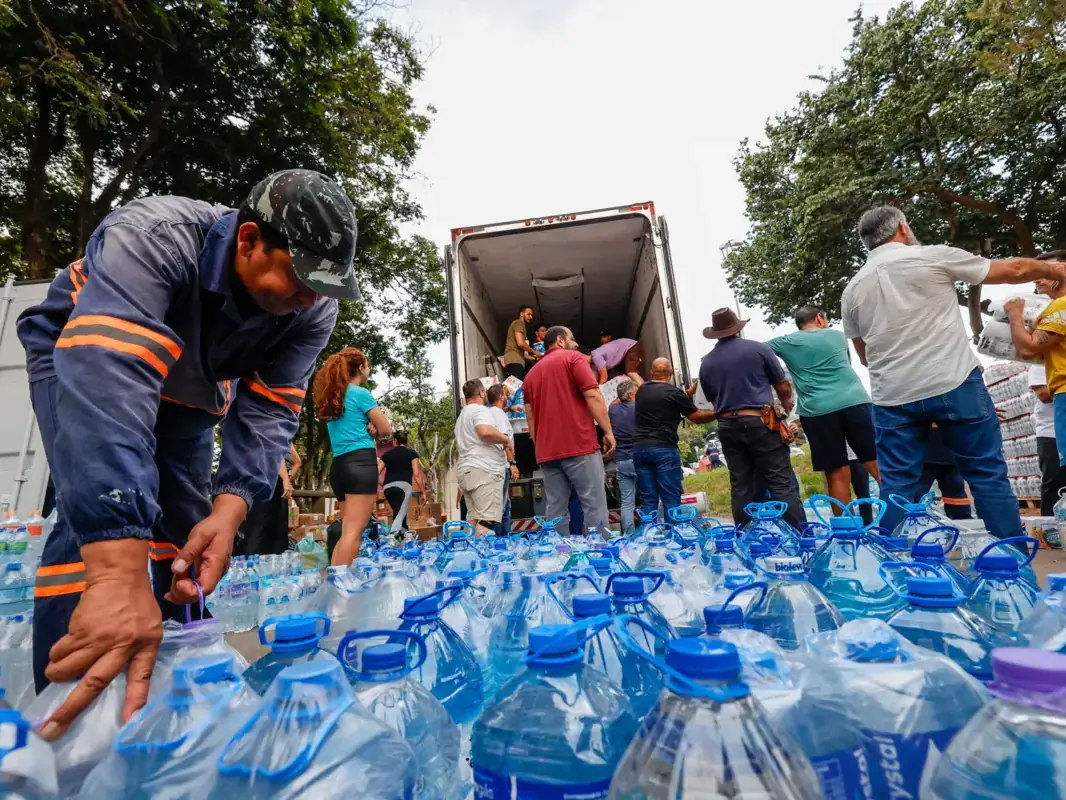 Colaboradores descarregam água potável para as vítimas das enchentes
